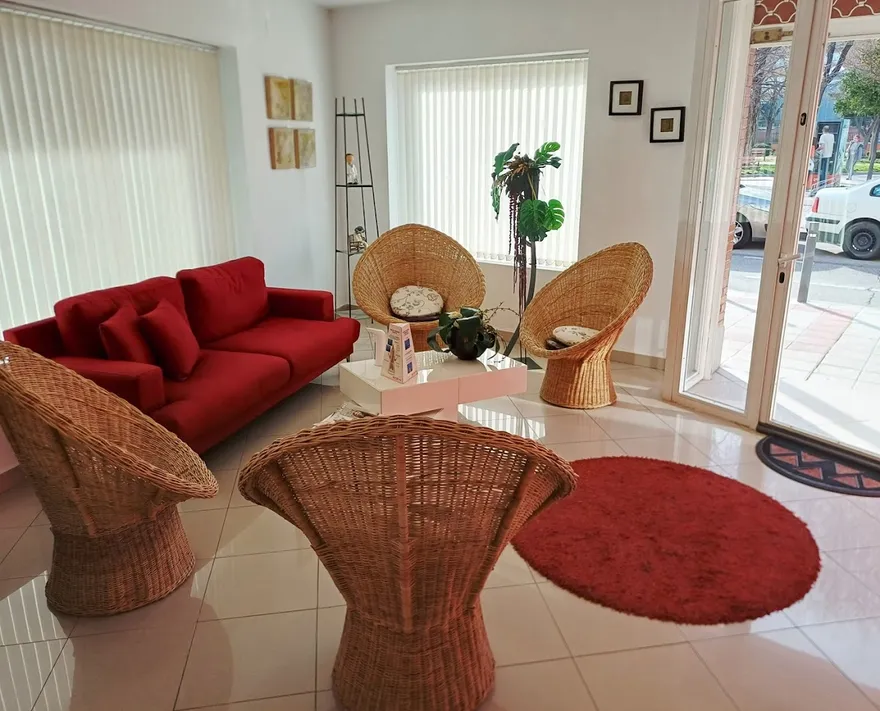 Sala de espera con sofá rojo y butacas de mimbre